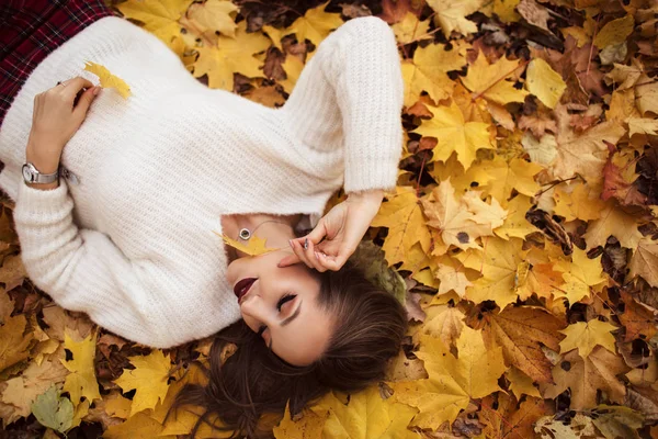 Mulher muito elegante com maquiagem de moda está deitado no tapete de folhas de bordo amarelo — Fotografia de Stock