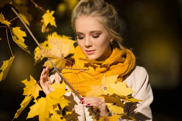 Hübsches blondes Mädchen in gelben Herbstblättern — Stockfoto