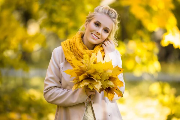 Pretty blonde girl with bouquet of yellow maple leaves — Stock Photo, Image
