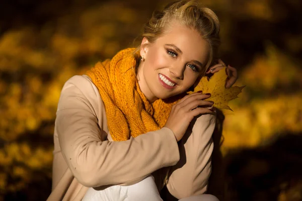 Ganska leende blond flicka i gul hösten lämnar — Stockfoto