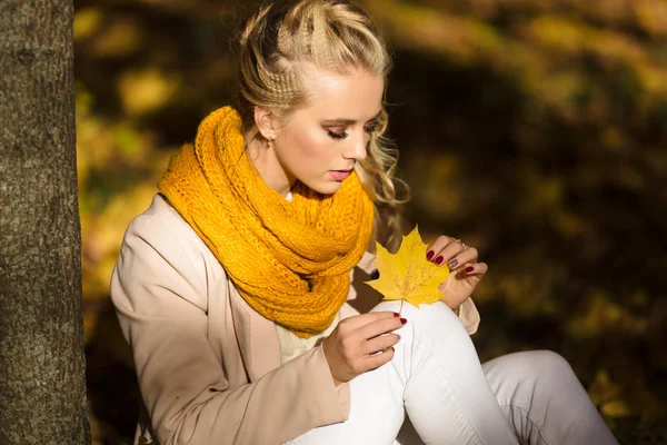 Pretty smiling blonde girl in yellow autumn leaves — Stock Photo, Image