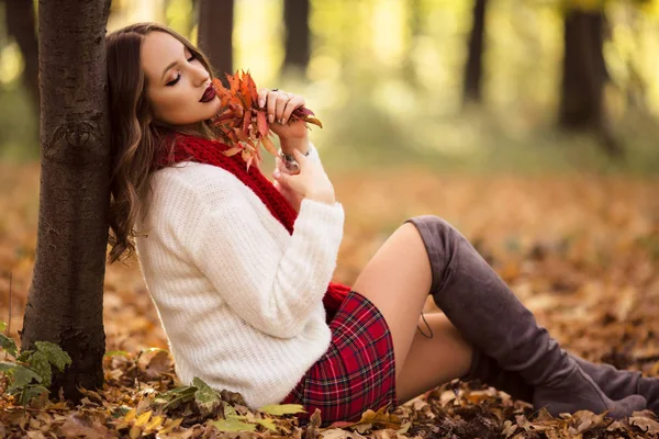 Mujer bonita está usando ropa de moda sentado en el parque de otoño —  Fotos de Stock