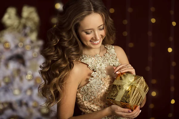 Menina feliz bonita está vestindo moda vestido dourado com caixa de presente — Fotografia de Stock