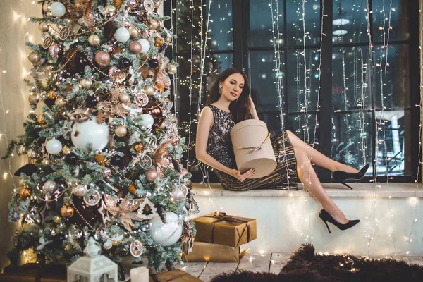 Vacker ung kvinna bär lyx klänning mot bakgrund av en julgran — Stockfoto