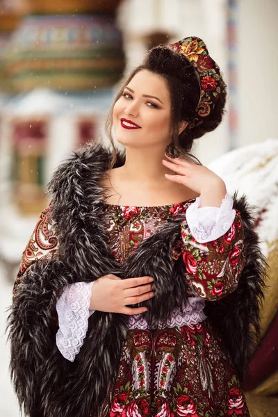 Mulher feliz bonita está vestindo roupas tradicionais russas no parque de inverno — Fotografia de Stock