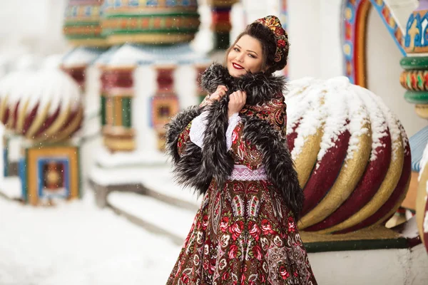 Hermosa mujer feliz está usando ropa tradicional rusa en el parque de invierno lleno de nieve — Foto de Stock