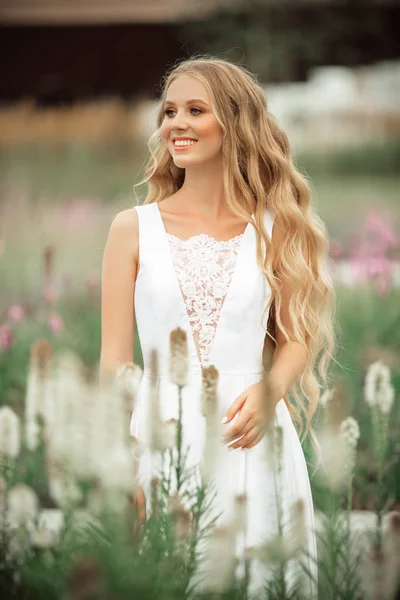 Feliz novia está usando vestido blanco en el parque de primavera con flores púrpuras —  Fotos de Stock