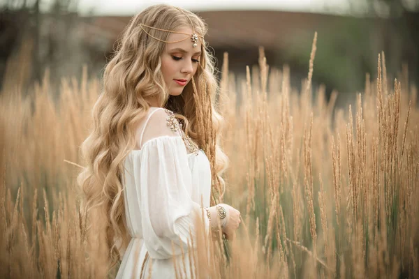 Happy fille blonde souriante porte une robe de mode blanche avec de longs cheveux blonds dans le domaine des rayons — Photo