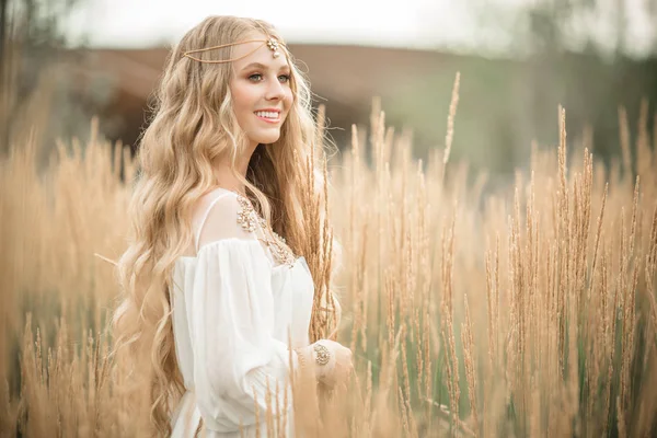 Feliz chica rubia sonriente está usando vestido de moda blanca con el pelo largo y rubio en el campo de rayos —  Fotos de Stock