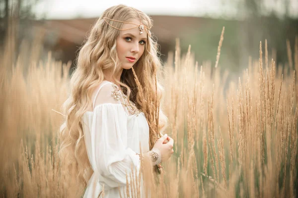 Feliz chica rubia sonriente con el pelo largo y rubio está usando vestido de moda blanca en el campo de rayos —  Fotos de Stock