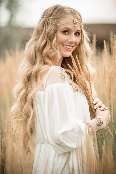 Feliz chica rubia sonriente con el pelo largo y rubio está usando vestido de moda blanca en el campo de rayos —  Fotos de Stock