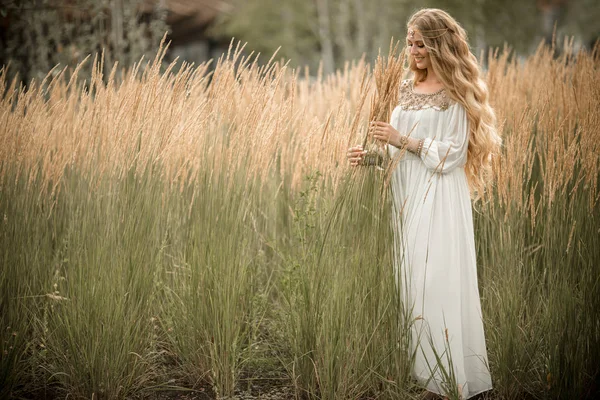 Portrait of happy smiling blonde girl with long blonde hair is wearing white bridal fashion dress on the nature in field of ray — Stock Photo, Image