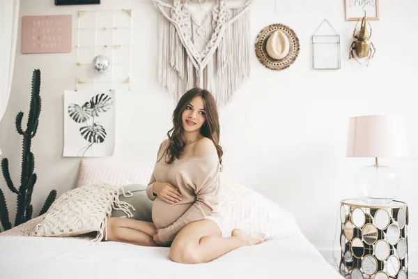 美丽的孕妇正坐在家里的床上 — 图库照片