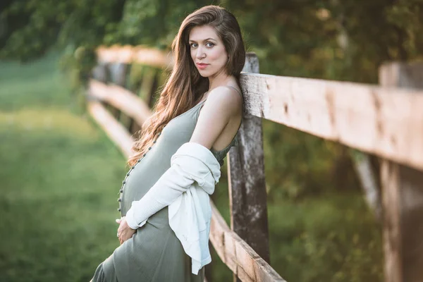 Mulher bonita grávida está posando no parque da primavera — Fotografia de Stock