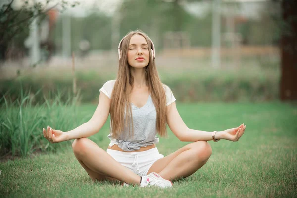 Jovem menina esportiva fazendo meditação de ioga no parque na cidade — Fotografia de Stock