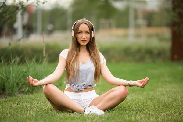 Joven chica deportiva haciendo meditación de yoga en el parque de la ciudad —  Fotos de Stock