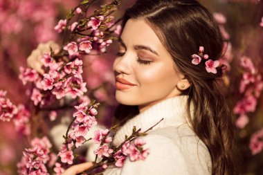 Pembe çiçekler ile çiçek ağacı yakın poz genç güzel gülümseyen kız portre.