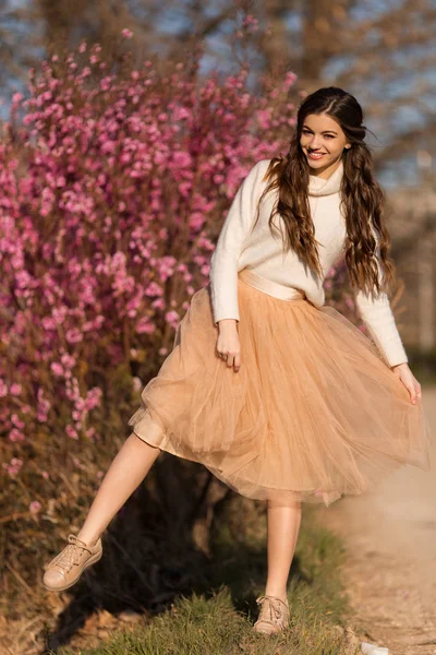 年轻美丽的少女与完美的皮肤穿着浪漫的衣服摆姿势附近的开花树在樱桃园 — 图库照片