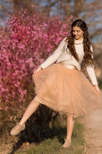 Young beautiful teen girl with perfect skin is wearing romantic clothes posing near blossom tree in cherry garden — Stock Photo, Image