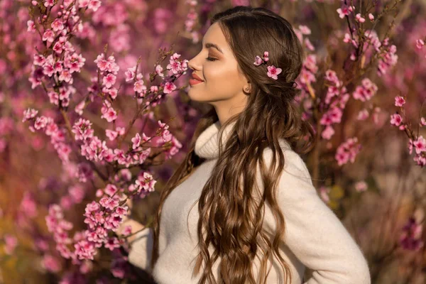 Mükemmel cilt ve makyaj ile genç güzel genç kız kiraz bahçesinde çiçek ağacı yakın poz romantik giysiler giyiyor — Stok fotoğraf