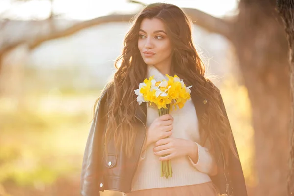 Porträt eines lächelnden Teenagermädchens mit langen Haaren hält einen Strauß Narzissenblumen in der Hand. Frühlingszeit — Stockfoto