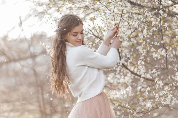 Jolie adolescente souriante posent dans le jardin près de cerisier en fleur avec des fleurs blanches. Printemps — Photo