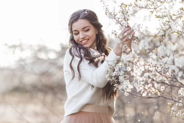 Pretty leende Teen Girl poserar i trädgården nära Blossom körsbärsträd med vita blommor. Vårtid — Stockfoto