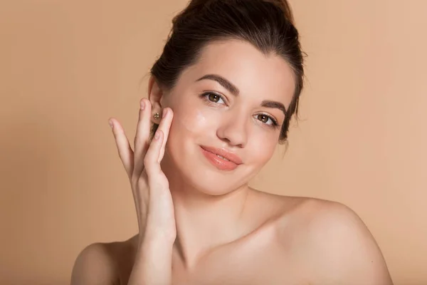 Hermoso retrato de la cara de la mujer joven está aplicando crema facial en una mejilla. Cuidado de la piel y concepto de salud . — Foto de Stock