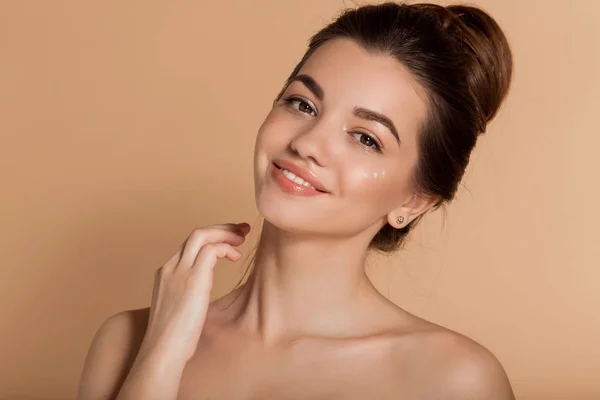 Hermoso retrato de la cara de la mujer joven está aplicando crema facial en una mejilla. Cuidado de la piel y concepto de salud . —  Fotos de Stock
