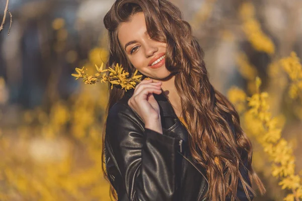 Retrato de una adolescente sonriente con el pelo largo está cerca de arbustos de aroma con flores amarillas. Primavera . —  Fotos de Stock