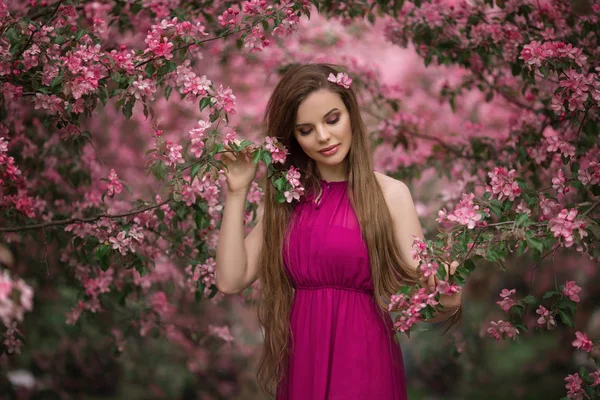 Jonge mooie vrouw in bloesem appeltuin met roze bloemen — Stockfoto