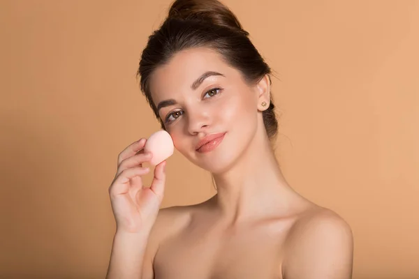 Closeup portré fiatal gyönyörű nő gazdaság szépségkeverő alkalmazása smink Alapítvány. Bőrápolási és szépségápolási koncepció. — Stock Fotó