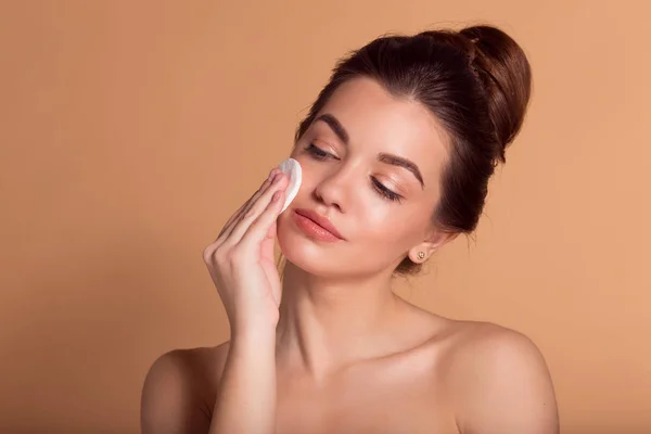 Retrato de jovem mulher bonita está limpando seu rosto de maquiagem com almofadas de algodão. Cuidados com a pele e conceito de beleza. — Fotografia de Stock