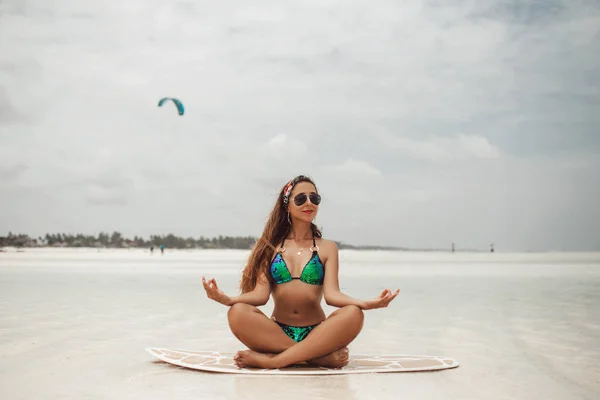 Junge sexy Frau mit sportlich gebräuntem Körper beim Sport auf dem Surfbrett am Strand an bewölkten Sommertagen bei Ebbe in Sansibar — Stockfoto