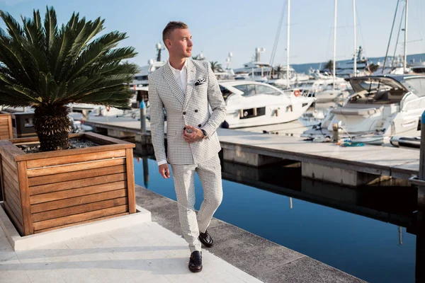 Elegante hombre de negocios lleva puestos de moda blanca en el fondo de la bahía con yates de lujo. Bahía de Montenegro . Imagen de stock