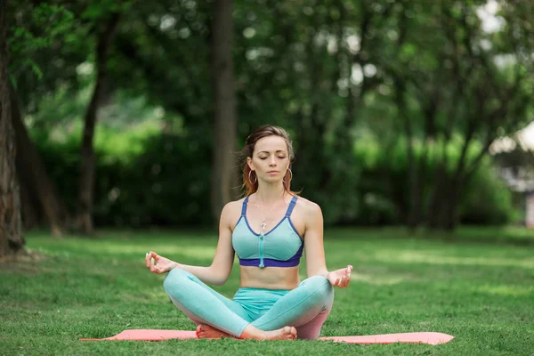 Mujer bonita joven haciendo yoga y estiramiento en el parque verde, hora de verano —  Fotos de Stock