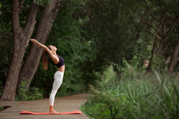 Pretty girl doing yoga and stretching outdoors in green park, summer time — Stock Photo, Image