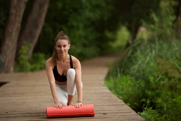 Chica bastante deportiva con esterilla de yoga al aire libre en el parque verde, hora de verano —  Fotos de Stock