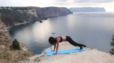 Nefes kesen deniz manzarası ile dağ kenarında yoga yapan güzel kadın.