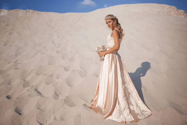 Beautiful bride is wearing fashion flying dress and wreath in the great desert in Dubai. — Stock Photo, Image