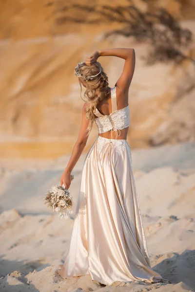 Hermosa novia está usando vestido de vuelo de moda y corona en el gran desierto de Dubai . — Foto de Stock