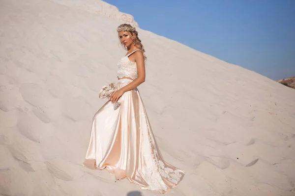 Hermosa novia está usando vestido de vuelo de moda y corona en el gran desierto de Dubai . — Foto de Stock