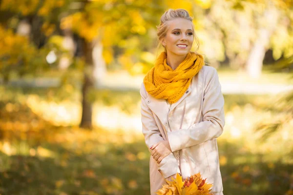 Portret van mooie blonde tiener meisje loopt in herfst Park met gele bladeren — Stockfoto