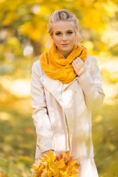 Portret van mooie blonde tiener meisje loopt in herfst Park met gele bladeren — Stockfoto