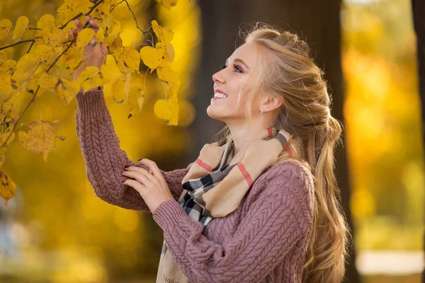 Happy pretty blonde teen girl is walking in autumn park with yellow leaves — Stock Photo, Image