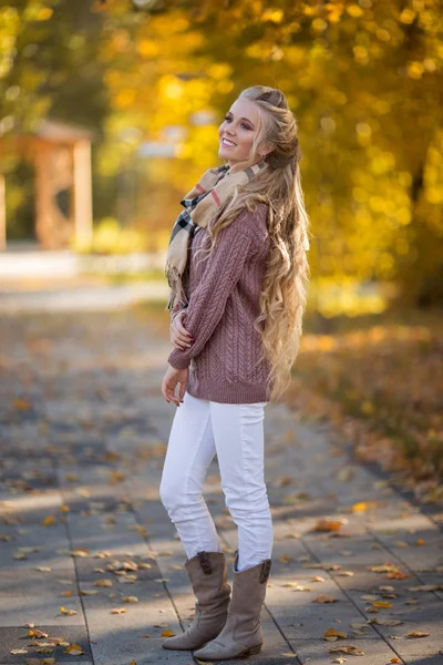 Feliz chica adolescente rubia bonita está caminando en el parque de otoño con hojas amarillas —  Fotos de Stock