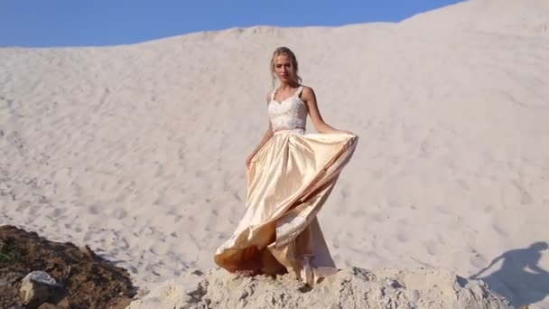 Bela noiva está vestindo vestido voador de moda e grinalda no grande deserto em Dubai . — Vídeo de Stock