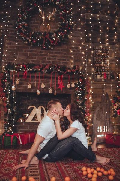 Linda mulher casal e homem estão se divertindo em casa com tangerinas. Tempo de Natal . — Fotografia de Stock