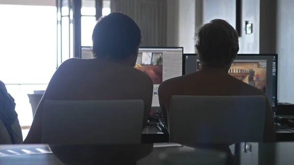 Two young men friends with bare chest at home sharing information and using computer. working on vacation.