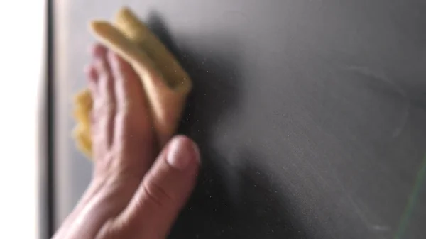 The mans hand wipes the chalkboard. Close-up.